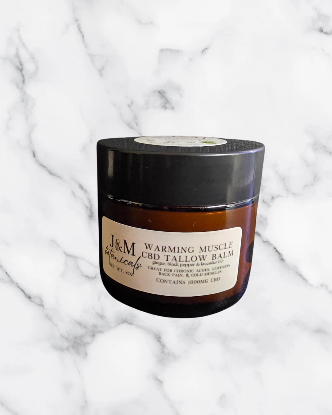 Jar of J&M Botanicals warming CBD tallow balm on a marble background