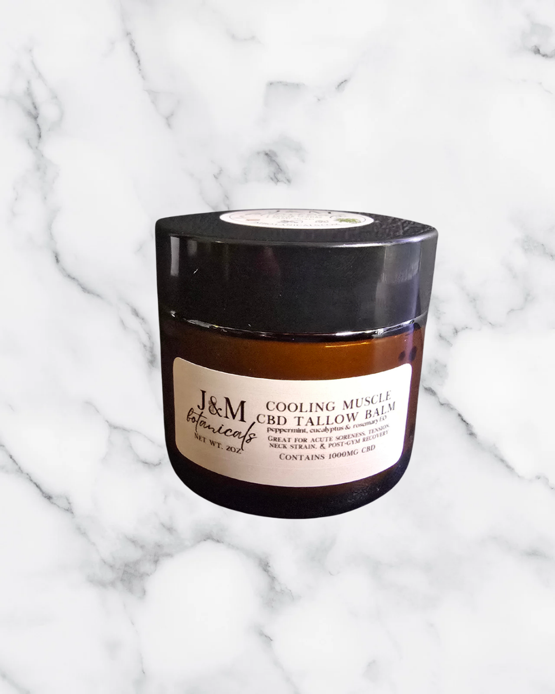 Jar of J&M cooling CBD tallow balm on a marble background