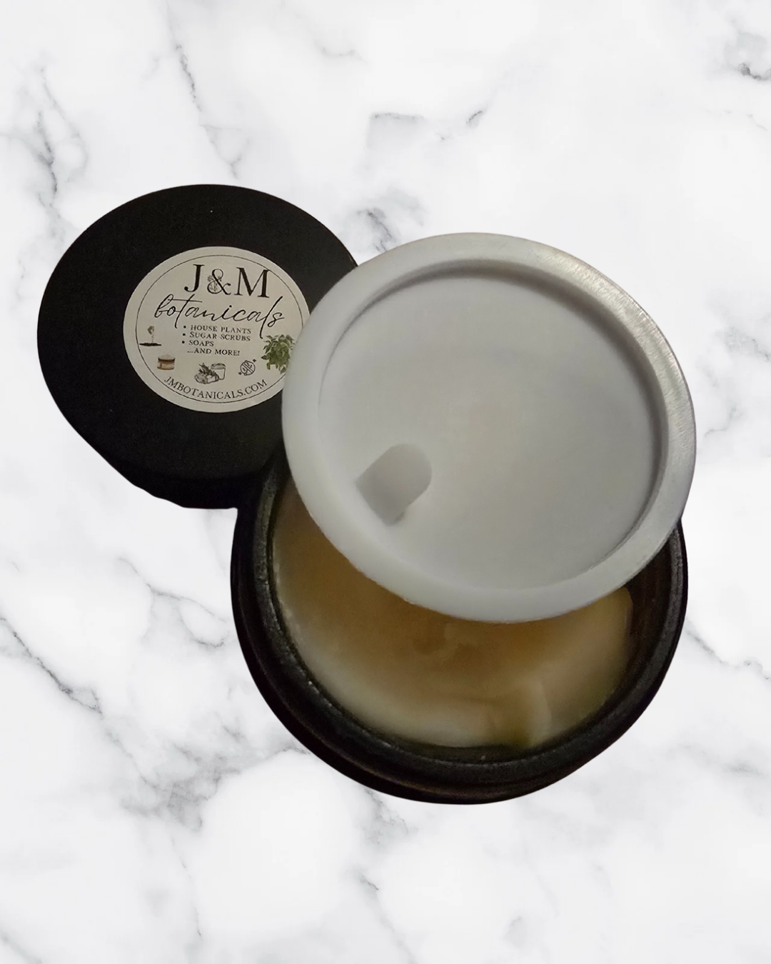 Jar of cream with a black lid on a marble surface